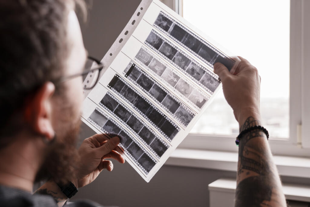 Photographer examining film negatives by window light